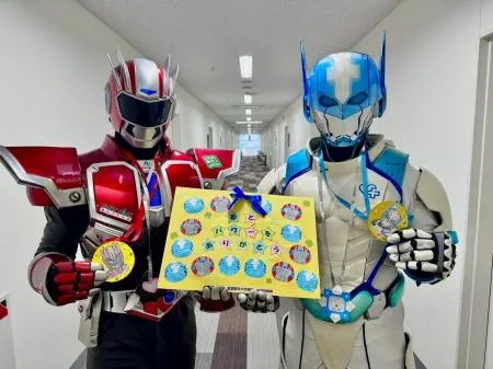 病院を訪問したヒーロー2人が、色とりどりの台紙を手にしている